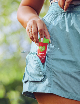 Energy Passionfruit Juice Shot being held by a woman and putting it into her pocket