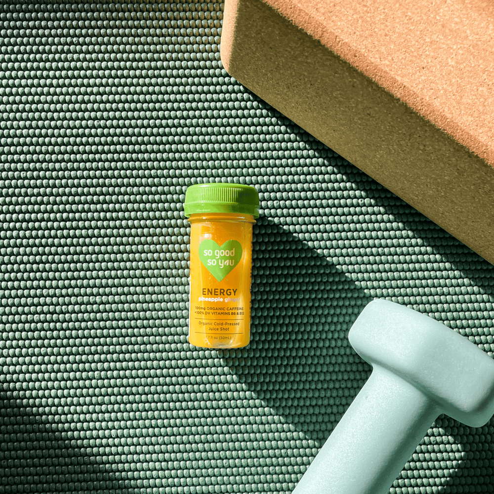 
                      
                        Energy Pineapple Ginger Juice Shot on yoga mat next to weight and yoga block
                      
                    