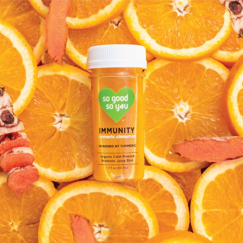 Immunity Turmeric Probiotic Juice Shot on top of raw turmeric and oranges